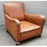 An early 20th century brown leatherette upholstered easy armchair, on turned beech supports,