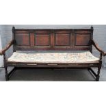 A George III oak open arm settle with four panel back on turned supports, 180cm wide x 102cm high.