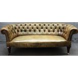 A Victorian green leather upholstered Chesterfield sofa, on turned mahogany supports,