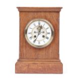 An Edwardian oak cased mantel clock with visible brocot escapement,