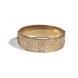 A 9ct gold hinged bangle, of oval hollow design, engraved to one side with scrolling foliage,
