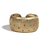 A gold and gem-set hinged torc bangle, star set with circular-cut sapphires,