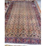 A Mashhad carpet, Persian, the pale fawn field with an allover herate design; a burgundy rosette,