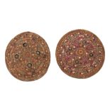 Two Indian Dhal shields, with embroidered covers with a repeated design on a maroon and rust ground,