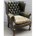 A George II style green leather upholstered wingback armchair, on claw and ball feet,