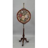 A Victorian carved walnut pole screen, with adjustable cylindrical brass column,
