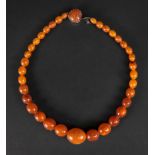 A reconstituted amber bead necklace, graduated from the centre, 53.5cm long.