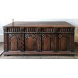 A reproduction 17th century style oak coffer, of panelled construction, with hinged top,