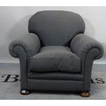 An early 20th century hardwood framed low armchair, with dark grey upholstery on two front bun feet,