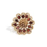 An 18 ct gold and garnet brooch, in a shaped circular abstract flowerhead shaped design,