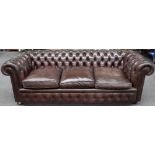 A brown leather upholstered button back Chesterfield sofa on bun feet, 228cm wide x 72cm high.