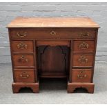An 18th century mahogany knee hole writing desk, with seven drawers about the cupboard,