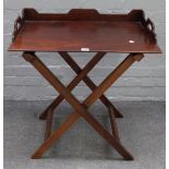 An early 19th century mahogany butler's tray, with three quarter gallery on folding stand,