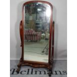 A late Victorian mahogany cheval mirror, with bevelled glass and scrolling supports,