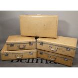 A group of five cream canvas suitcases, the largest 76cm wide x 22cm high.