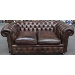 A brown leather upholstered button back Chesterfield sofa on bun feet, 175cm wide x 70cm high.