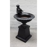 A black painted cast iron urn, cast with a seated cherub on square base, 55cm diameter x 98cm high.