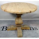 A modern pine circular dining table, on tapering column and X-frame base,