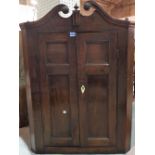 An 18th century style oak hanging corner cupboard, with panelled doors, 77cm wide x 104cm high.
