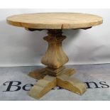 A modern pine circular dining table, on tapering column and x-frame base,
