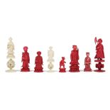 A group of eight Chinese carved ivory chess pieces, six stained red and two natural,