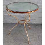 A white painted wrought iron circular French bistro table, on three shaped supports,