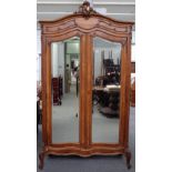 A 19th century French walnut armoire, with 'C' scroll crest over a pair of mirrored doors,