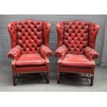 A pair of George II style red leather upholstered wingback armchairs on block supports,