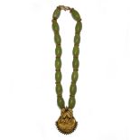 An Asian gold and pale green stone pendant necklace, the hollow gold pendant of crescent form,