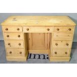 An early 20th century pine kneehole desk, with nine drawers about the knee on a plinth base,
