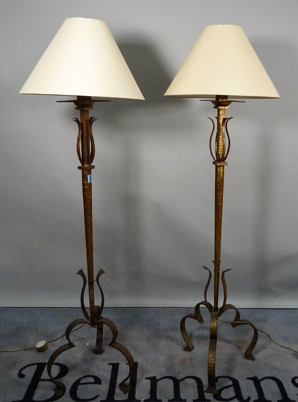 A modern pair of gold painted metal standard lamps, on scrolling supports and shades, 153cm high.