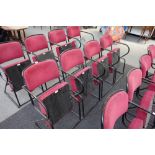 A bank of four red upholstered folding theatre seats, on black metal tubular frames,