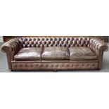 A large brown leather upholstered button back Chesterfield sofa, on bun feet,