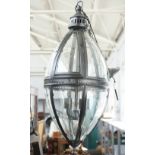A modern patinated metal lantern of ovoid form, with glazed panels,
