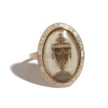 A gold and white enamelled mourning ring, circa 1800, the centre glazed with a hairwork urn,