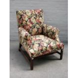 A George III mahogany framed tapestry upholstered easy armchair, on blind fret mahogany supports,