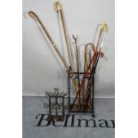 Six various canes in a wrought-iron stick stand, 38cm wide x 76cm high,