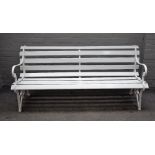 A white painted garden bench, with cast iron ends and wooden slats, 187cm wide x 82cm high.
