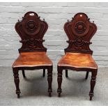 A pair of Victorian mahogany cartouche back hall chairs, on baluster supports,