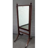 A George III mahogany cheval mirror, with urn finials on four downswept supports,