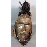 A modern tribal mask with feather plume and shell decoration, 46cm high.