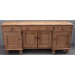 A Victorian pine dresser base with three drawers over four cupboards on turned feet,
