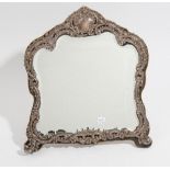 A silver mounted strut backed mirror, the mount embossed and pierced with floral,