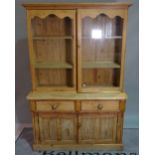 An early 20th century pine display cabinet, over two short drawers and cupboard base,