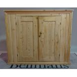 An early 20th century pine side cabinet, the moulded panel doors on plinth base,