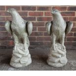 A pair of reconstituted stone figures of eagles perched on rocks, 59cm high.