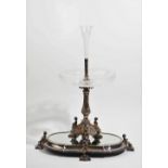 A silver plated metal mounted glass table centrepiece, the base with three seated putto,