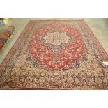 A machine made carpet of Persian design, the red field with a round medallion, 345cm x 250cm.