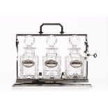 A silver plated tantalus, 20th century, with three cut glass decanters having silver labels,
