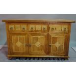 A modern oak and marble inlaid sideboard, with three short drawers over cupboard doors on bun feet,